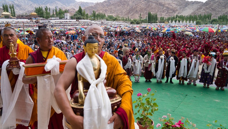 Miembros de la comunidad llevando ofrendas pasan frente a Su Santidad el Dalái Lama mientras los artistas locales actúan detrás de ellos, durante la ceremonia de la Ofrenda de Larga Vida en Leh, Ladakh, J&K, India, el 30 de julio de 2017. Foto de Tenzin Choejor/OHHDL 