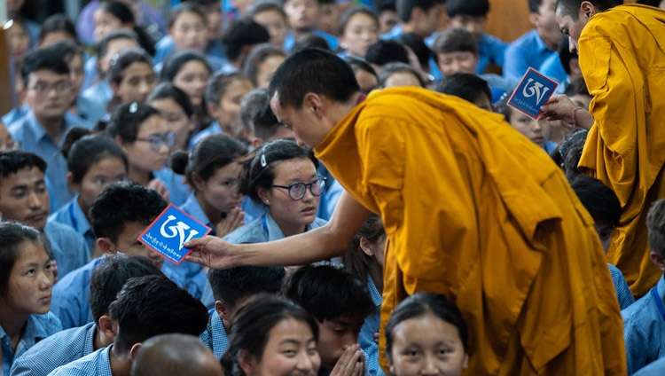Asistentes moviéndose entre la audiencia con objetos rituales mientras Su Santidad el Dalái Lama otorga la iniciación de permiso de Manjushri Blanco en el último día de sus enseñanzas para jóvenes estudiantes tibetanos en el Templo Principal Tibetano en Dharamsala, HP, India el 8 de junio de 2018. Foto de Tenzin Choejor