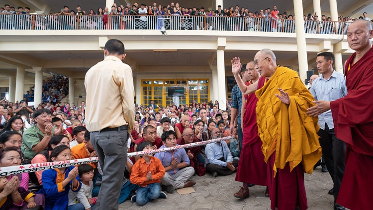 Su Santidad el Dalái Lama saludando a los miembros de la audiencia sentados en el patio del Templo Principal Tibetano mientras regresa a su residencia al concluir sus enseñanzas para jóvenes estudiantes tibetanos en el Templo Principal Tibetano en Dharamsala, HP, India el 8 de junio de 2018. Foto de Tenzin Choejor