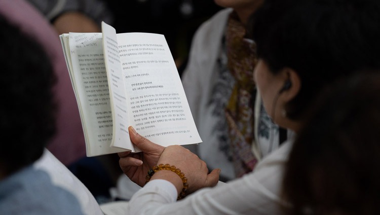  Una de las personas de la audiencia sigue el texto durante el segundo día de las enseñanzas de Su Santidad el Dalái Lama en el Templo Principal Tibetano en Dharamsala, HP, India, el 5 de septiembre de 2018. Foto de Tenzin Choejor