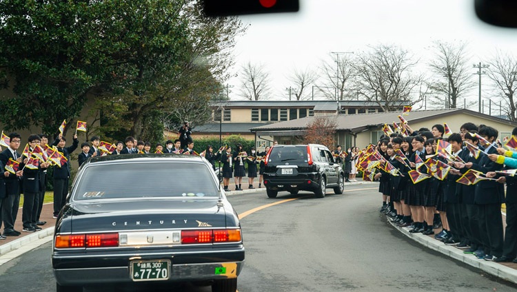 Estudiantes y personal sonriendo y ondeando banderas tibetanas dan la bienvenida a Su Santidad el Dalái Lama a su llegada a la Universidad de Reitaku en Chiba, Japón, el 19 de noviembre de 2018. Foto de Tenzin Choejor