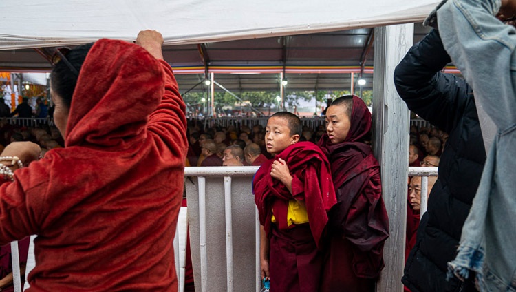 Jóvenes monjes encontrando protección contra la lluvia durante el discurso de Su Santidad el Dalái Lama ante la multitud antes de llevar a cabo una ceremonia de empoderamiento de Avalokiteshvara en el terreno de Kalachakra en Bodhgaya, Bihar, India, el 3 de enero de 2020. Foto de Tenzin Choejor