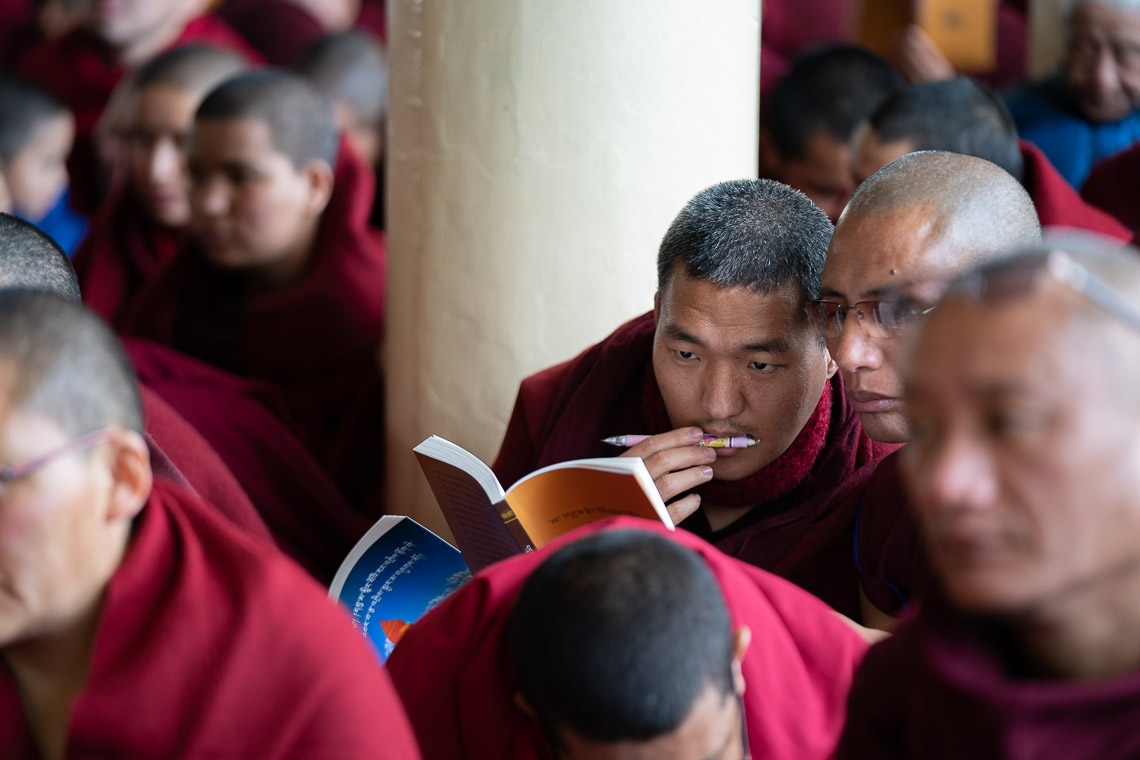 Los monjes en la audiencia siguen el texto mientras Su Santidad el Dalái Lama lee de la Esencia del Camino Medio de Bhavaviveka en el primer día de sus enseñanzas en el Templo Principal Tibetano en Dharamsala, HP, India el 20 de febrero de 2019. Foto de Tenzin Choejor