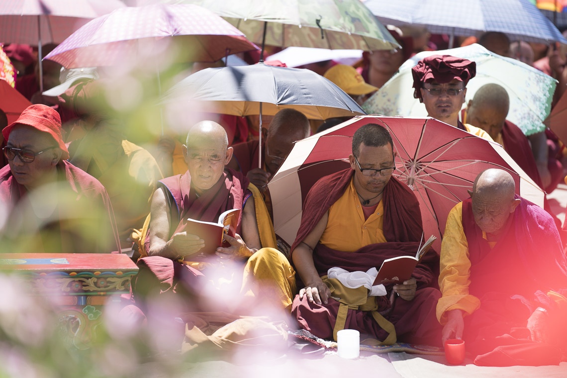 Protegiéndose del sol con paraguas, los monjes siguen el texto que Su Santidad el Dalái Lama lee, la «Guía de la Forma del Vida del Bodisatva» en el primer día de sus enseñanzas en Leh, Ladakh, J&K, India el 28 de julio de 2017. Foto de Tenzin Choejor/OHHDL