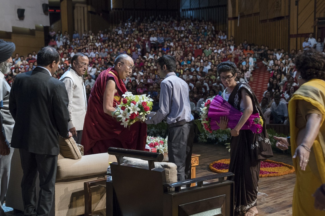 El comité de bienvenida de la Association of British Scholars ofrece a Su Santidad el Dalái Lama guirnaldas de flores al comienzo de su charla en el auditorio del Fuerte Siri de Nueva Delhi, India, el 10 de agosto de 2017. Foto de Tenzin Choejor/OHHDL 
